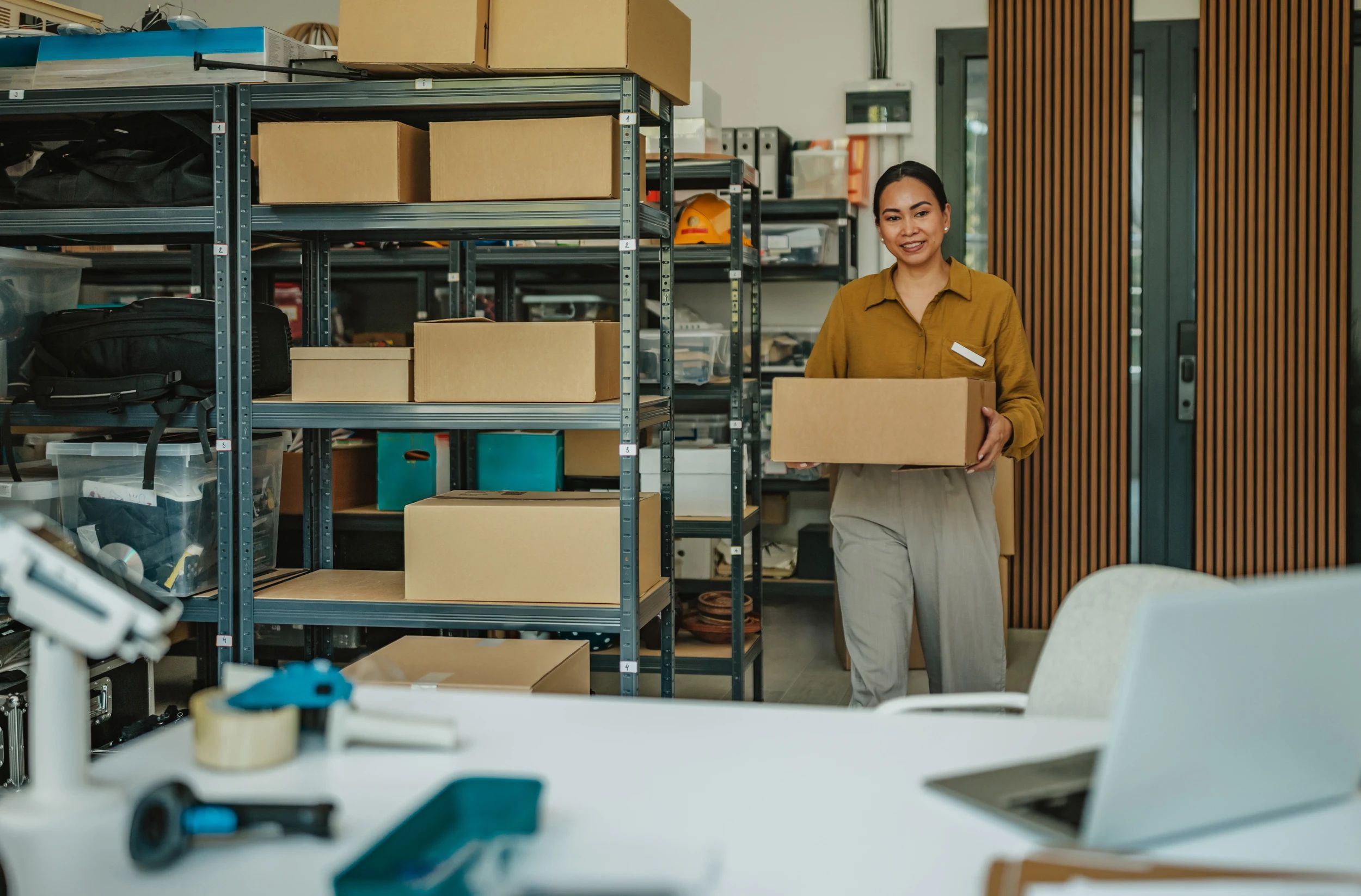Warehouse worker carrying a carton past numbered shelving holding mixed client stock